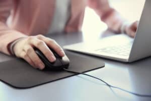 Woman Using Laptop With Wired Mouse on the Table