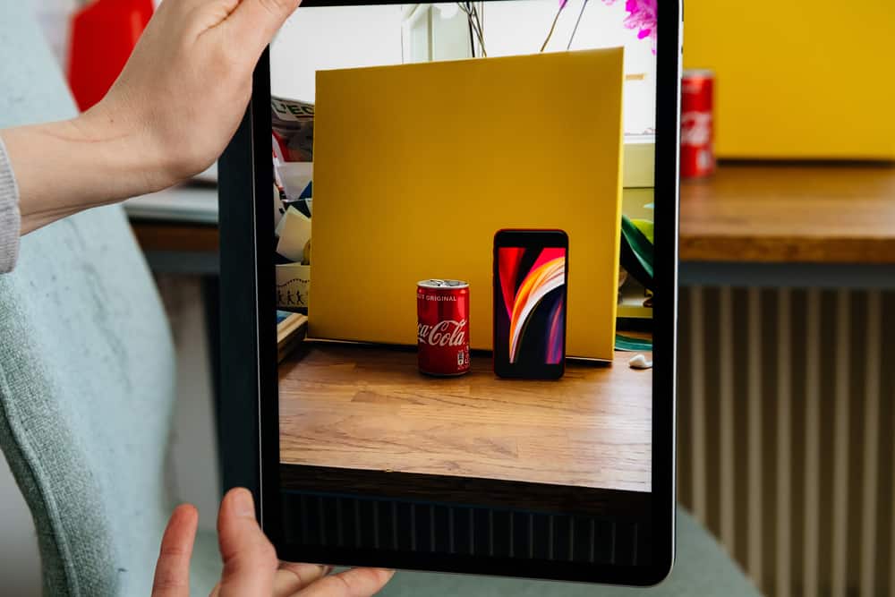 iPad photograph of an iPhone beside a Coke can