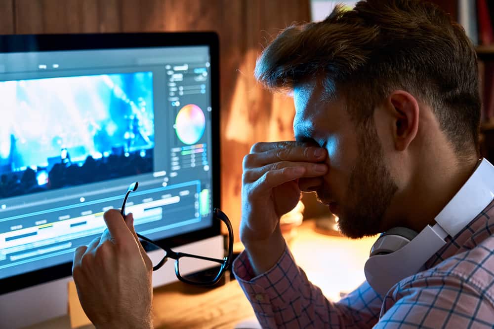 Man rubbing eyes at computer